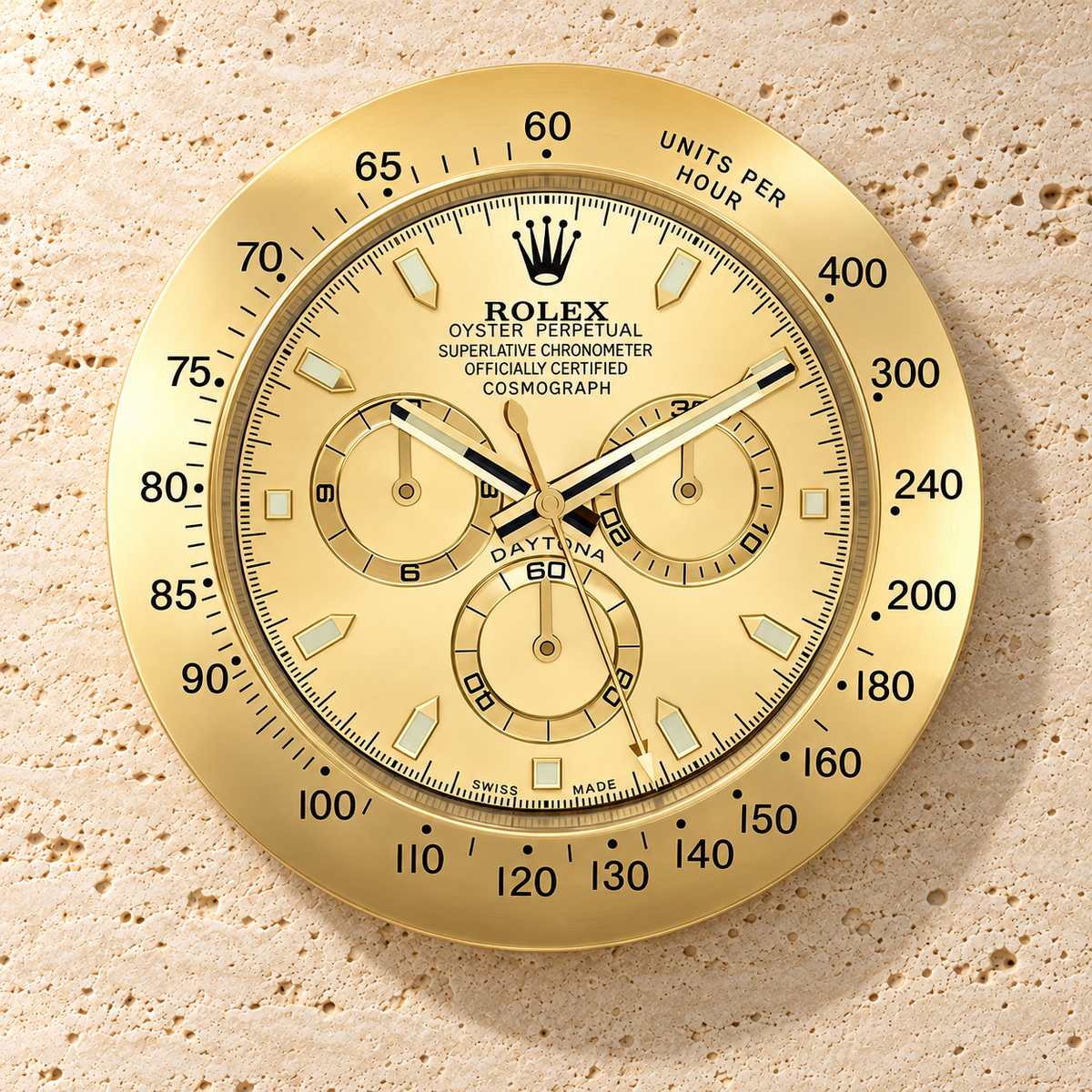 Daytona Wanduhr – Komplett in Goldoptik – Vorderansicht an einer hellen Steinwand