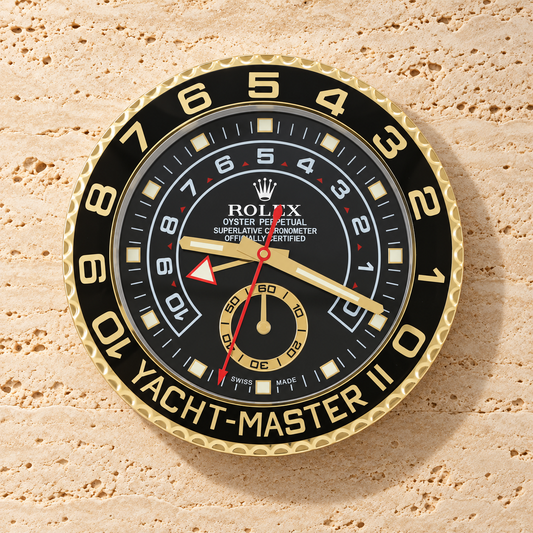 Yacht-Master II Wanduhr – Gold & Schwarz an einer hellen Travertinwand