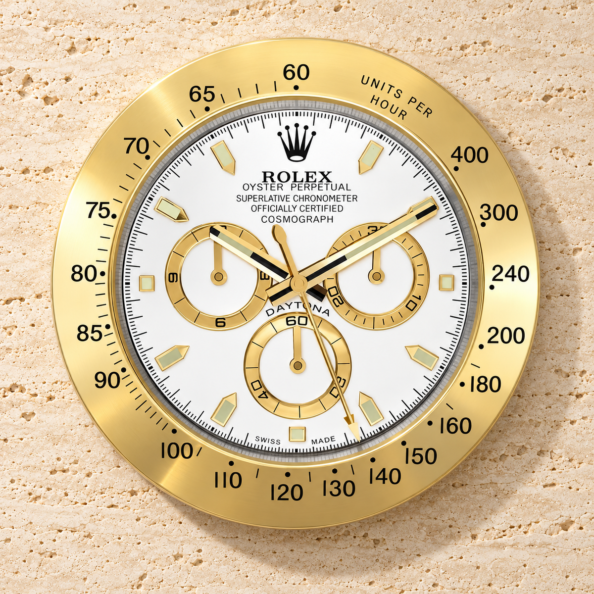 Daytona Wanduhr in Gold und Weiß mit drei goldfarbenen Zifferblattringen an einer hellen Steinwand