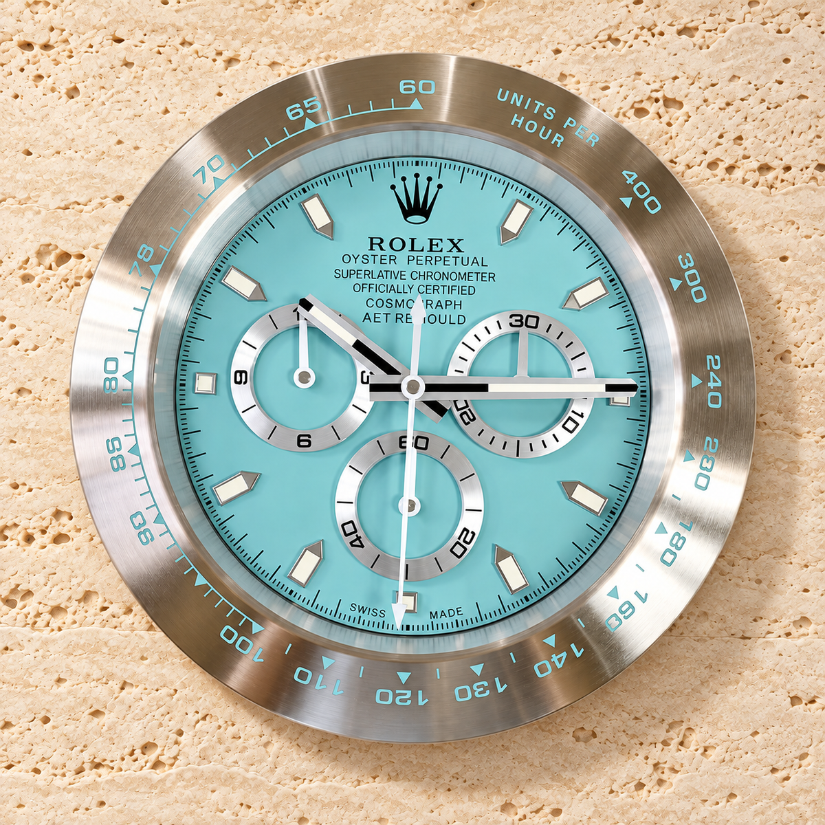 Daytona Cosmograph Wanduhr – Platinfarbenes Zifferblatt – Vorderansicht an heller Travertinwand